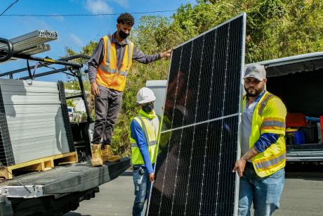 Three men moving a solar panel