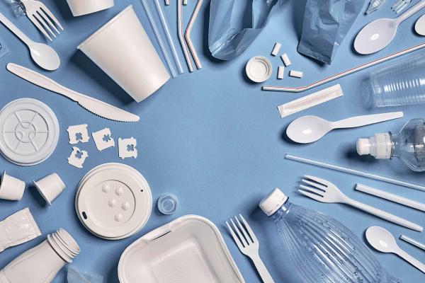 A bunch of plastic cutlery and assorted items on a blue tablecloth