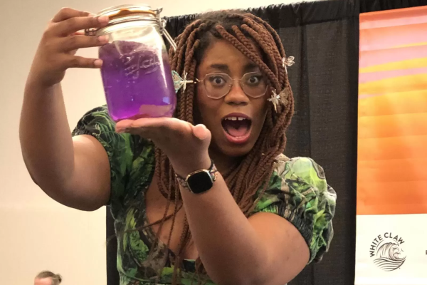 Alexis Nikole Nelson, aka the black forager, holds up a jar of bright purple spiderwort soda