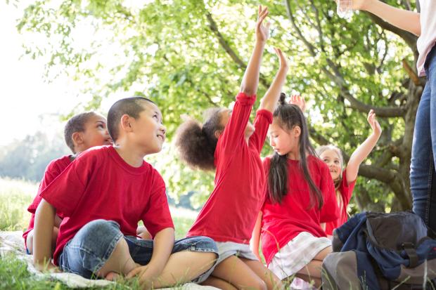 Children seated in a part with lots of greenery