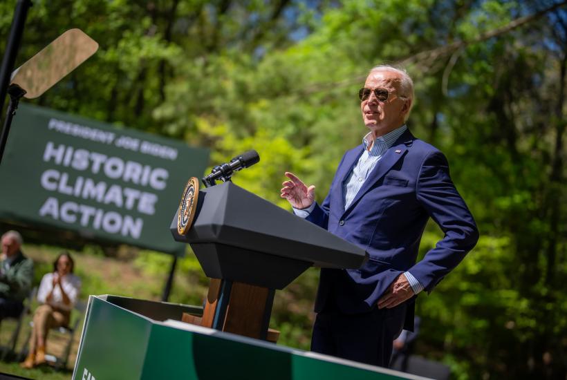President Joe Biden standing at a podium in front of a sign that reads historic climate action