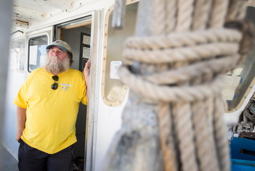 Keith “Buddy” Guindon standing at the door to a fishing boat with a rope tied up in the foreground