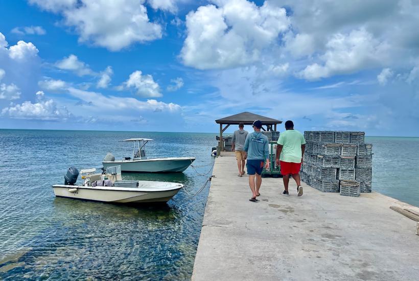 Group of men walking on a dock next to 2 docked boats