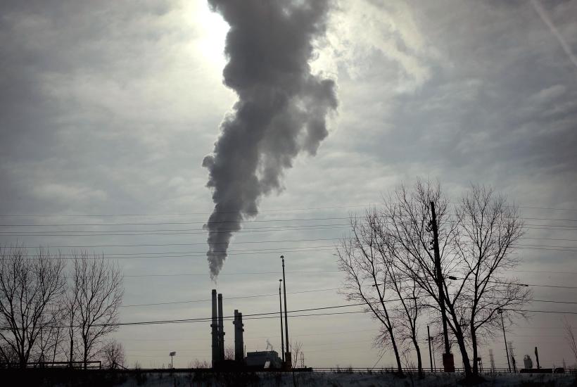 A plume of smoke blotting out the sun coming out of a coal power plant
