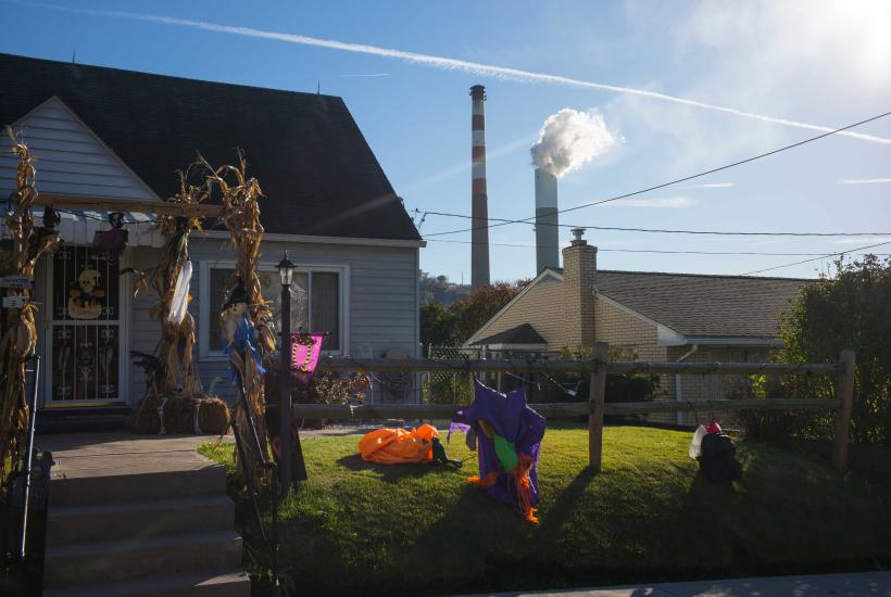 A residential home with two towering smokestacks in the background