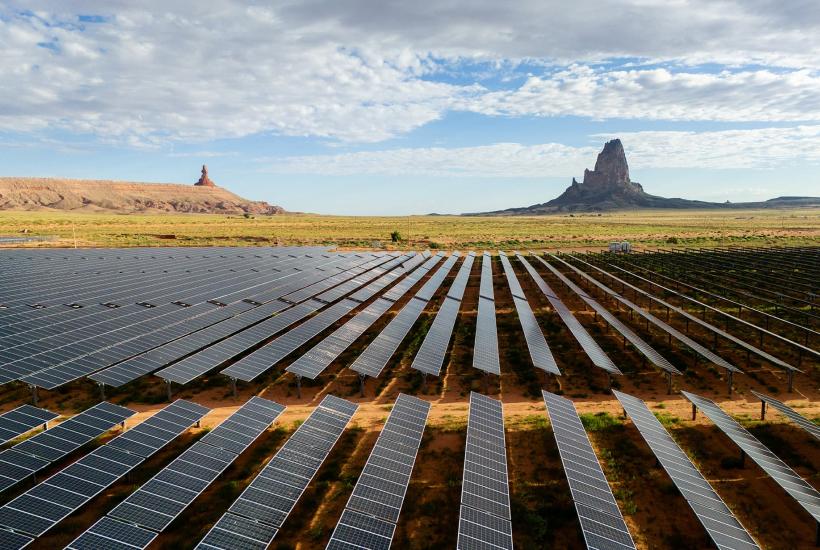 Rows of solar panels in Arizona with large mountainous rock formations in the far background