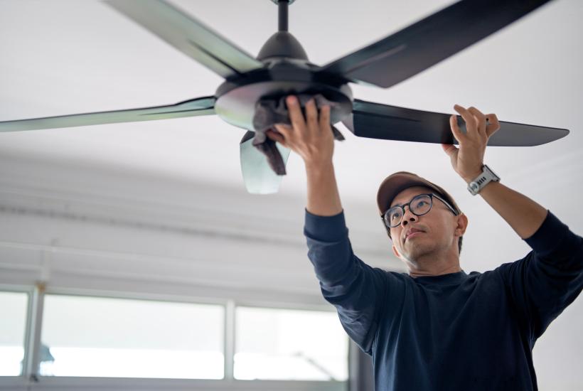 A man installing a ceiling fan